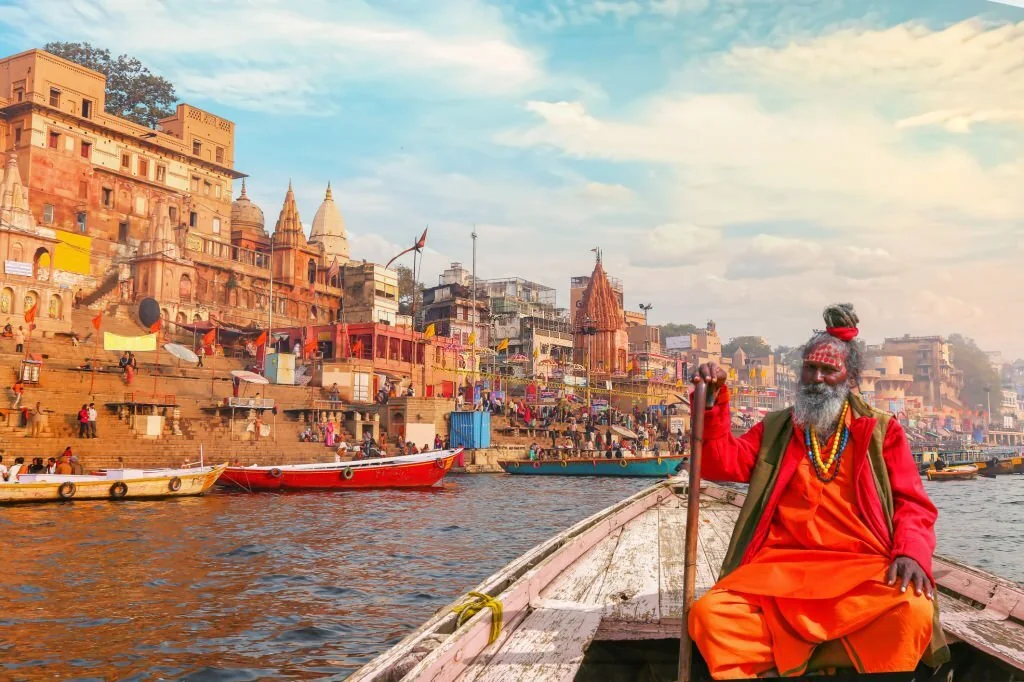 Sadhu en barque devant les ghats de Varanasi au bord du Gange