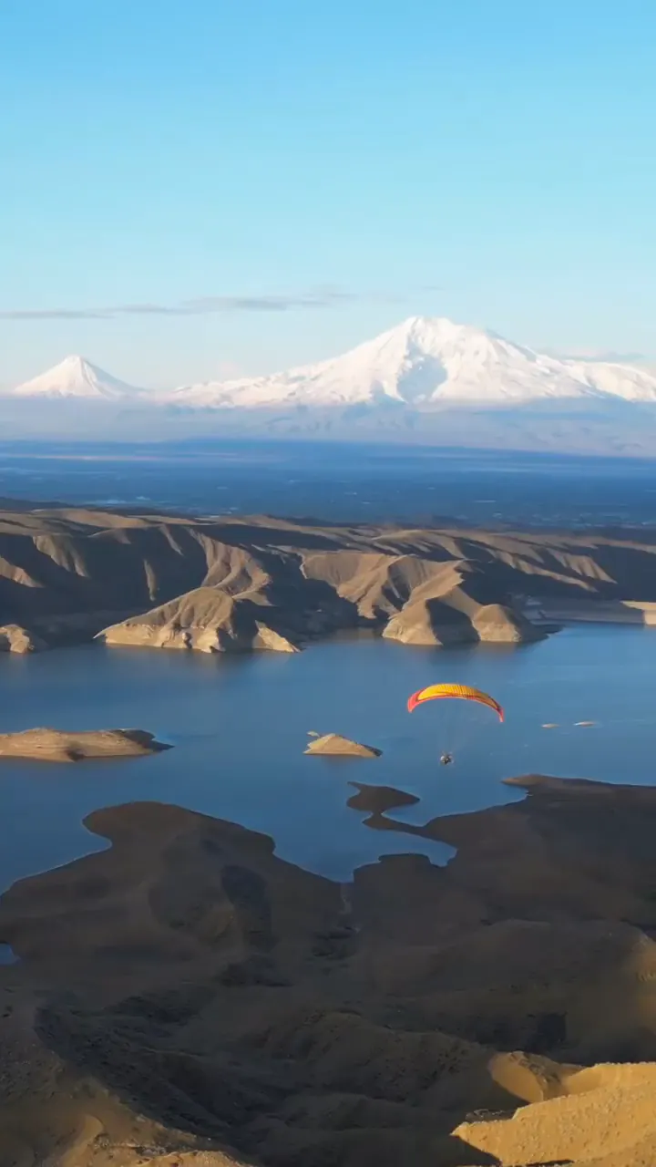 Le lac et les reliefs arméniens face au mont Ararat, survolés par un parapente